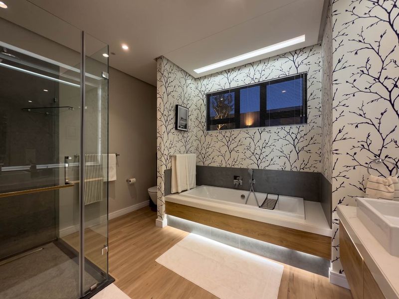 Modern bathroom featuring a glass-enclosed shower, a built-in bathtub with ambient under-lighting, and stylish patterned wallpaper.