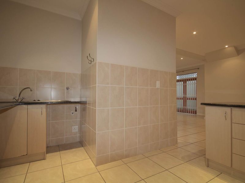 A functional kitchen area featuring light-toned cabinetry, granite countertops, tiled splashbacks, and neutral floor tiles, offering a clean and practical workspace.