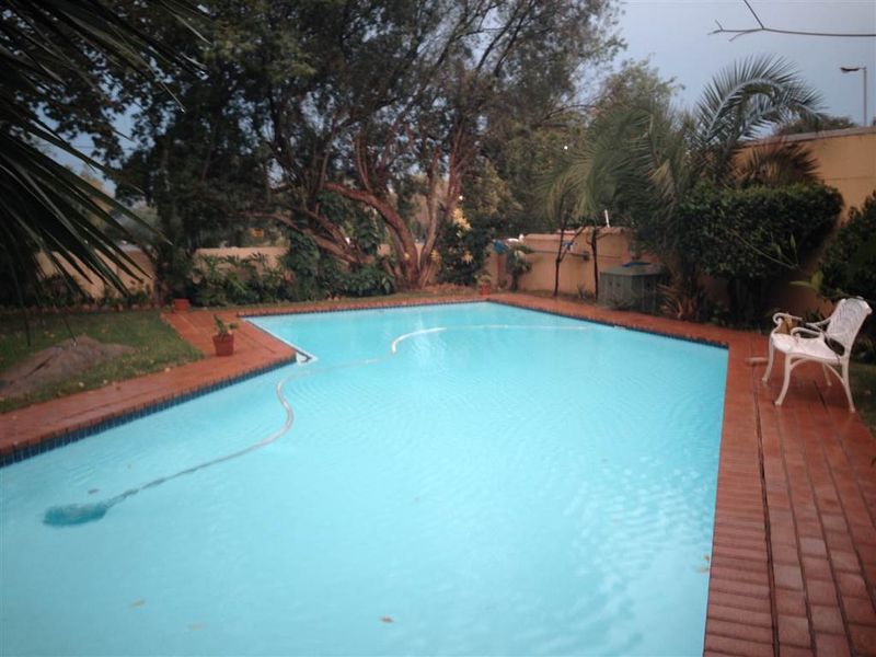 A private swimming pool area featuring brick coping and surrounding garden landscaping, providing a functional outdoor space for recreation.