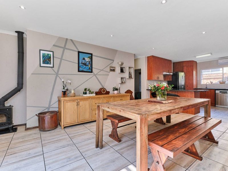 Spacious open-plan living and dining area featuring a wood-burning stove, tiled flooring, and a functional kitchen with built-in cabinetry.