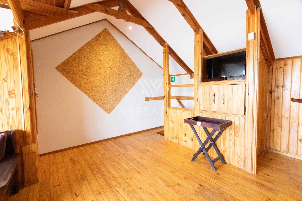 Attic-style bedroom featuring exposed timber roof trusses, wood paneling, and integrated storage cabinetry.
