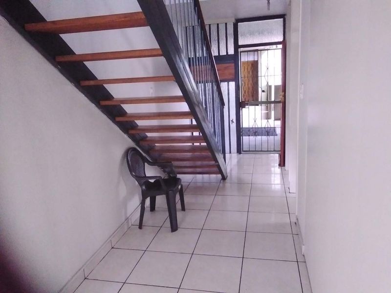 Entrance area featuring tiled flooring and an open-tread staircase with a metal balustrade, leading to a secure exterior door.