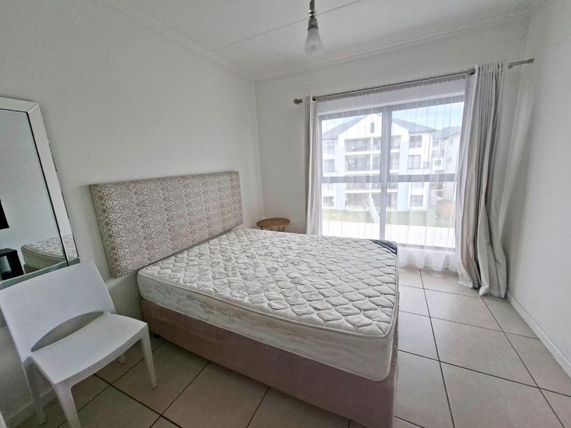 A bright bedroom featuring tiled flooring and a large sliding glass door that provides natural light and access to the exterior.