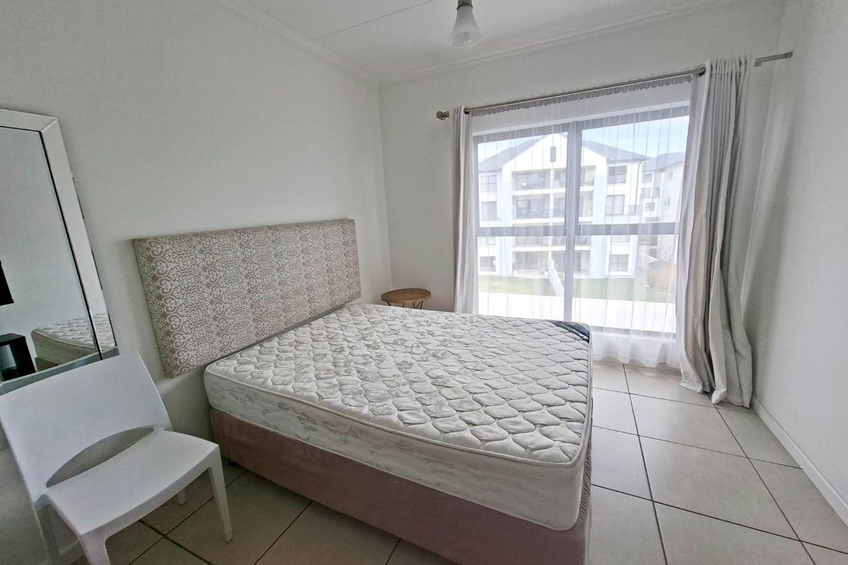 A bright bedroom featuring tiled flooring and a large sliding glass door that provides natural light and access to the exterior.
