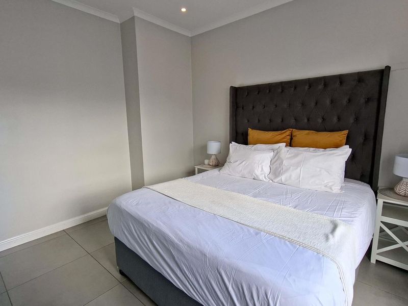 A well-maintained bedroom featuring neutral wall tones, tiled flooring, and recessed ceiling lighting, providing a clean and functional living space.