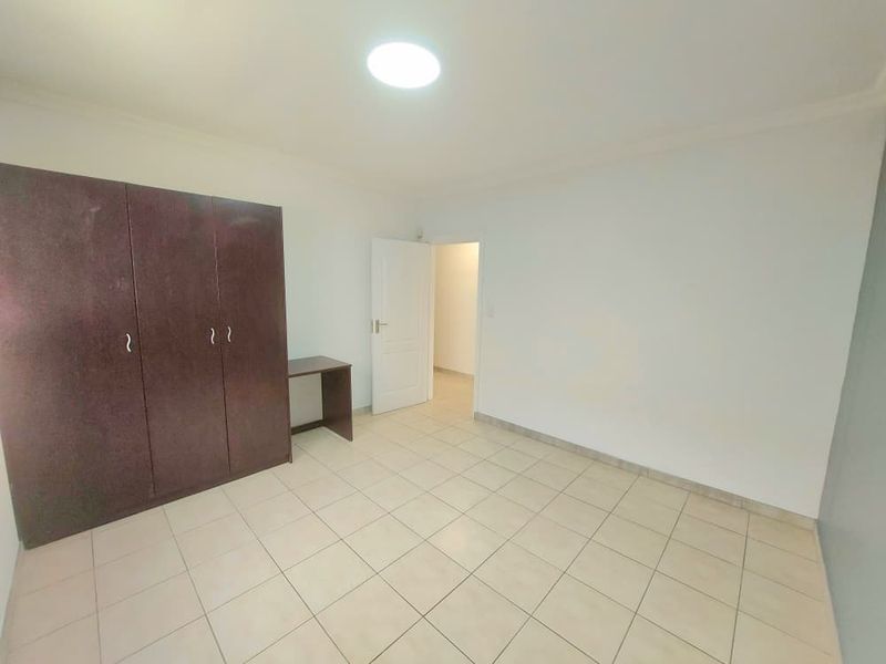 A clean, empty bedroom featuring neutral tiled flooring and a large built-in wardrobe, offering a blank canvas for personalization.