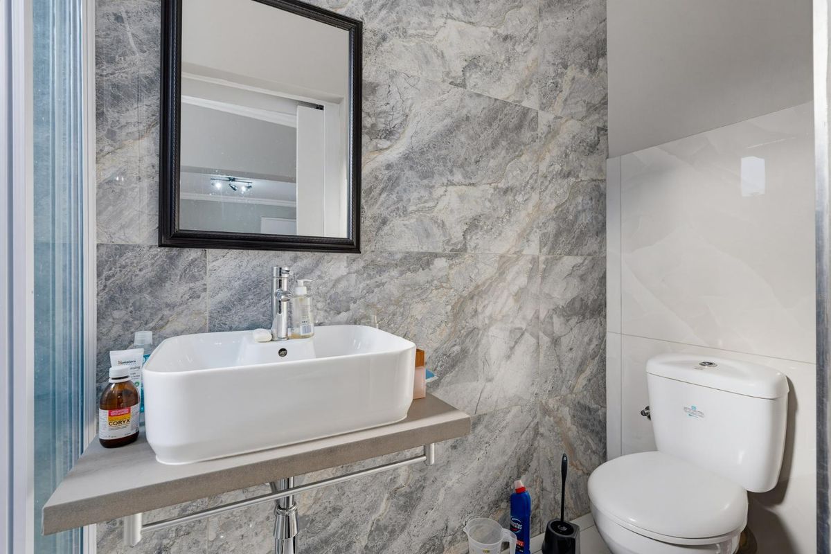 Modern bathroom featuring a vessel sink on a wall-mounted shelf, chrome fixtures, and elegant marble-effect wall tiling.