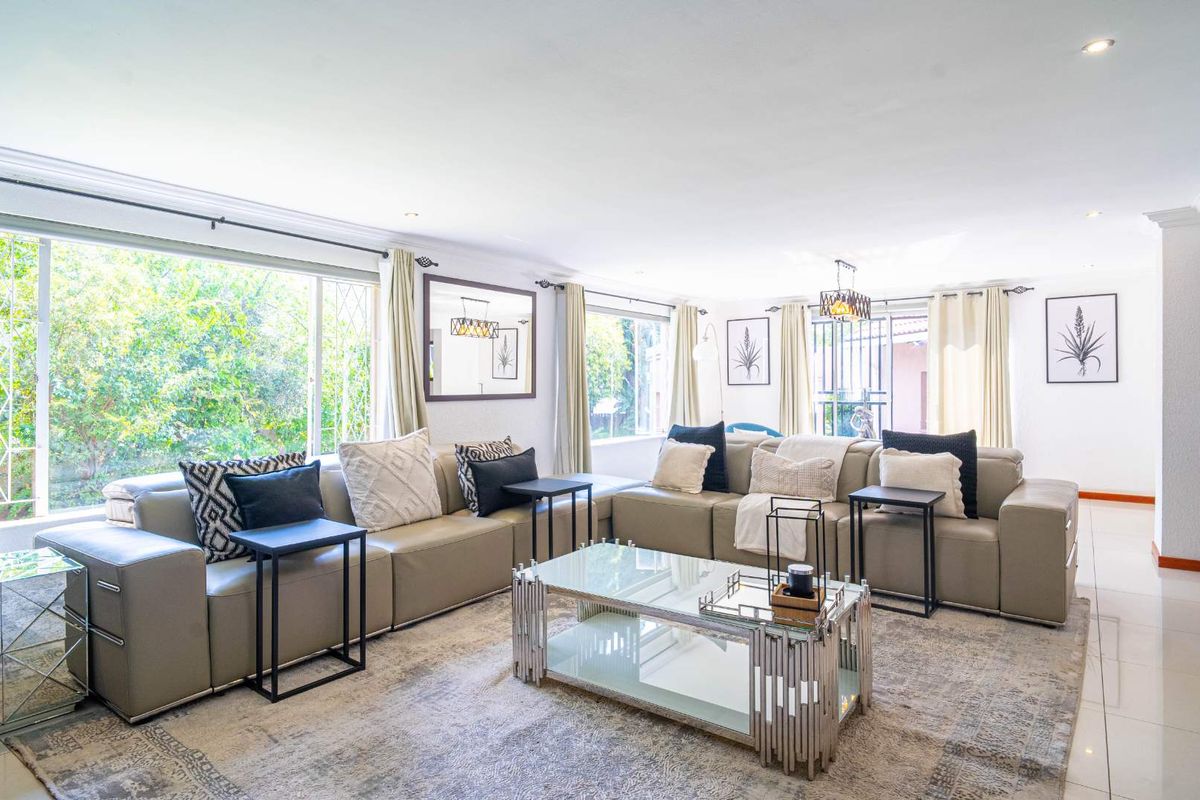Spacious and bright living room featuring large windows, recessed downlighting, and neutral tiled flooring, creating a comfortable and inviting atmosphere.