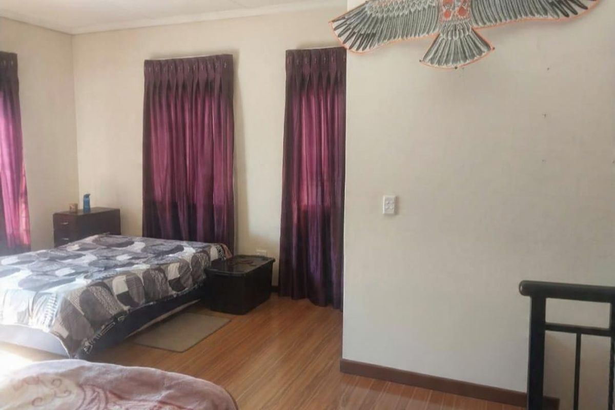 A bedroom featuring laminate wood flooring and dual window treatments, providing a functional and neutral living space.