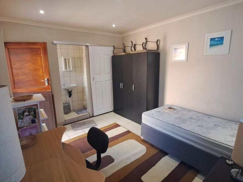 A functional bedroom featuring an en-suite bathroom, built-in wardrobe, and recessed lighting, offering a practical layout for comfortable living.