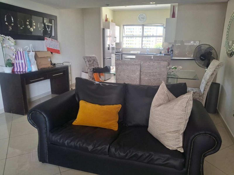 Open-plan living and dining area featuring tiled flooring and recessed lighting, seamlessly connected to a functional kitchen space.
