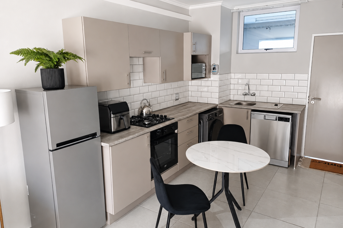 A modern, well-maintained kitchen featuring neutral cabinetry, subway tile backsplash, integrated appliances, and tiled flooring, offering a clean and functional cooking space.