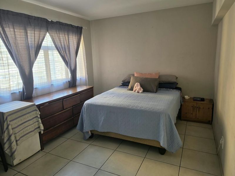 A functional bedroom featuring tiled flooring and a large window, providing a neutral base for personalization.