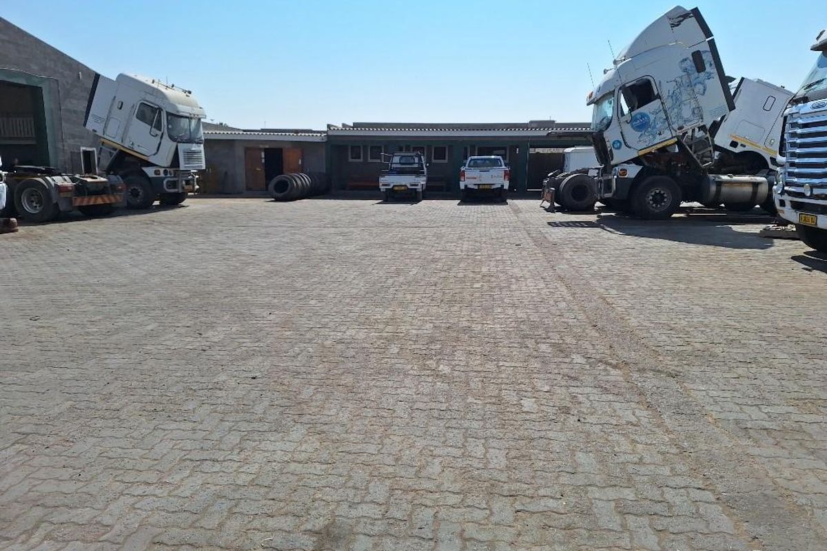 Spacious industrial yard with paved surface and access to warehouse buildings, suitable for heavy vehicle parking and logistics operations.