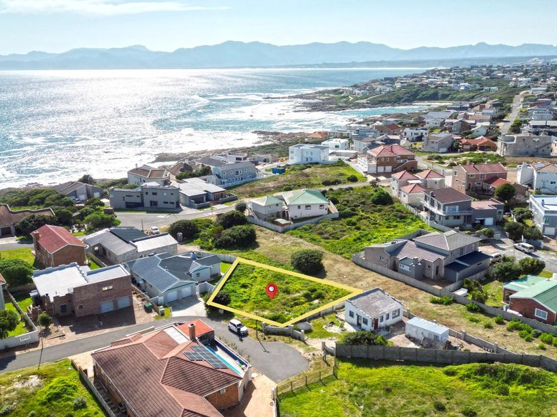Aerial view of a vacant residential plot situated in a coastal neighborhood with scenic ocean views.