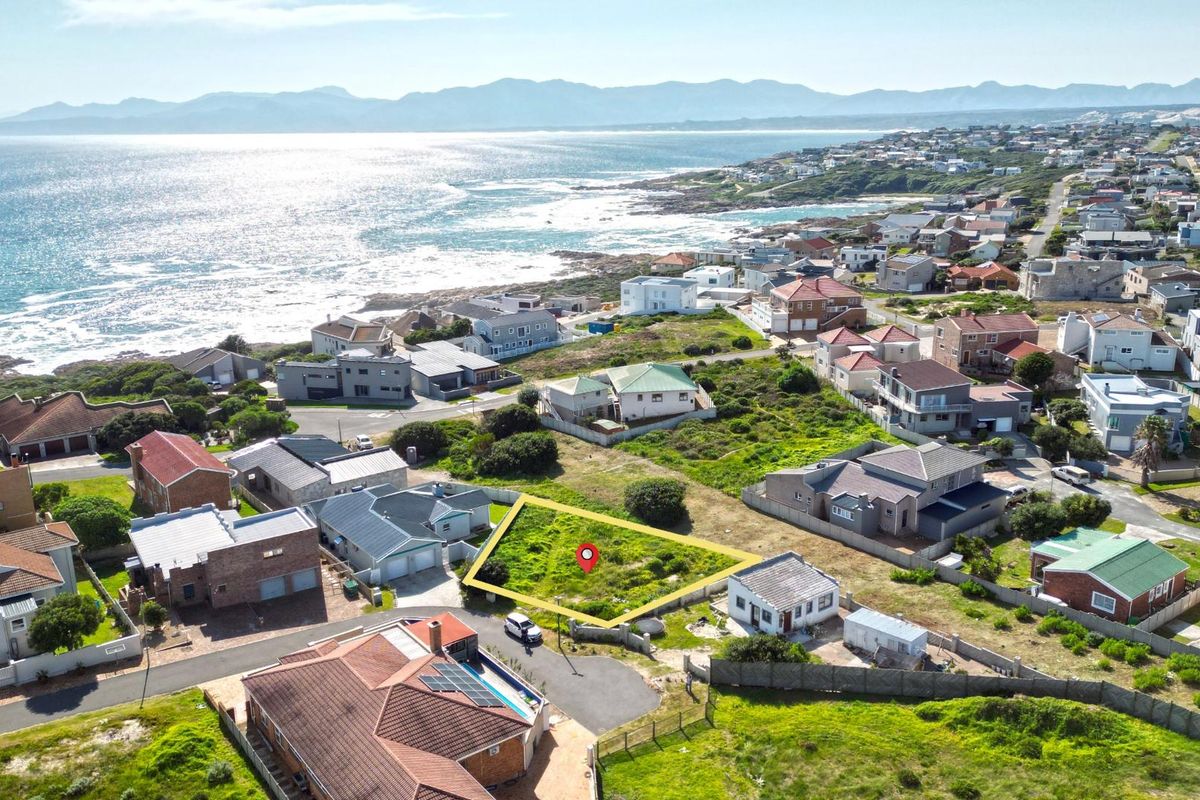 Aerial view of a vacant residential plot situated in a coastal neighborhood with scenic ocean views.