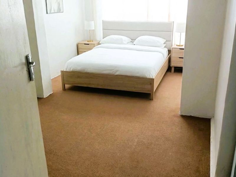 A bedroom featuring carpet flooring and a curtain rod, providing a functional space with neutral finishes.