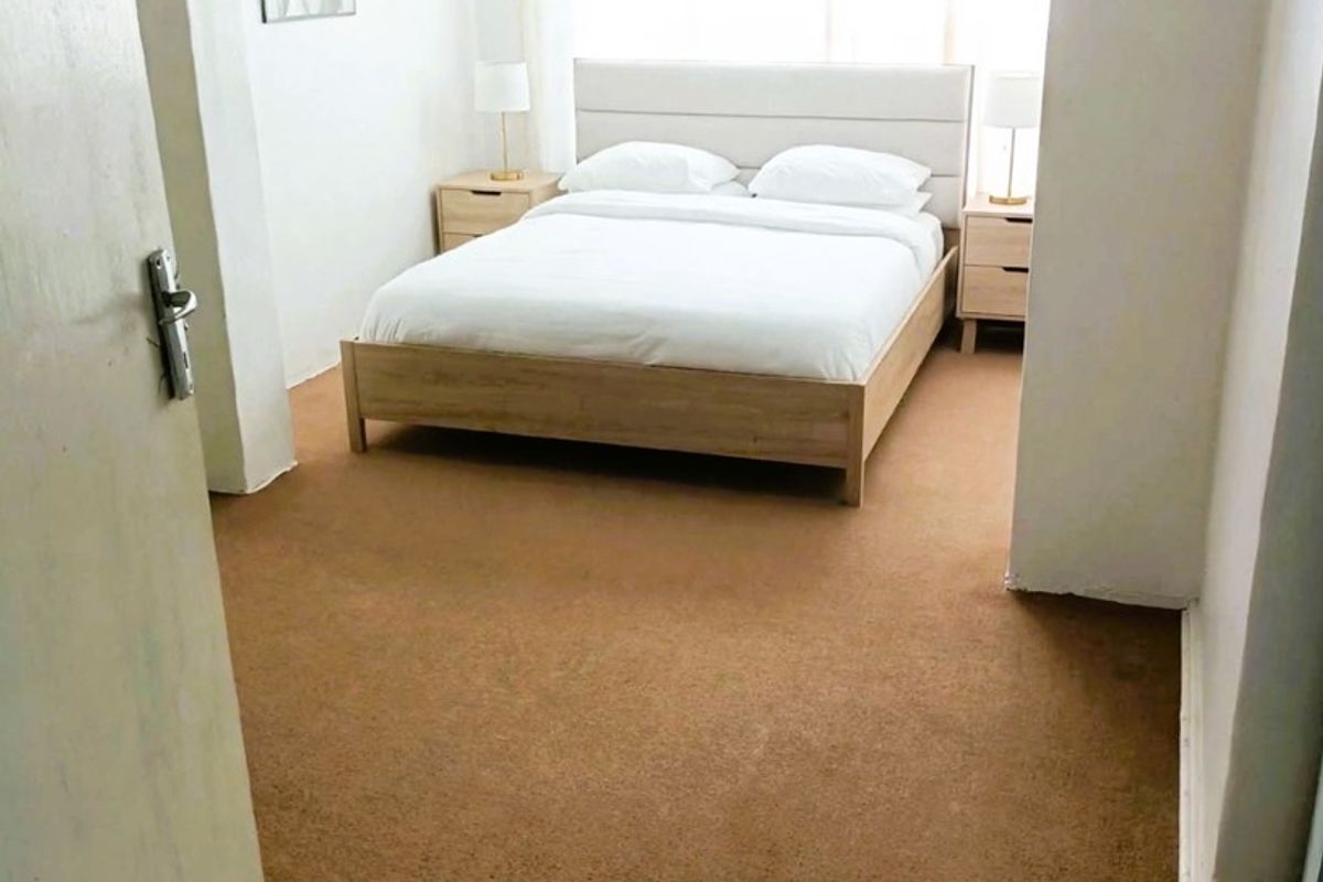 A bedroom featuring carpet flooring and a curtain rod, providing a functional space with neutral finishes.