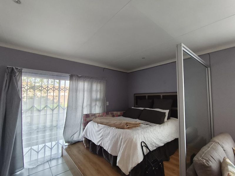Bedroom featuring a raised wooden platform, sliding glass door with security gate, and a built-in room divider.