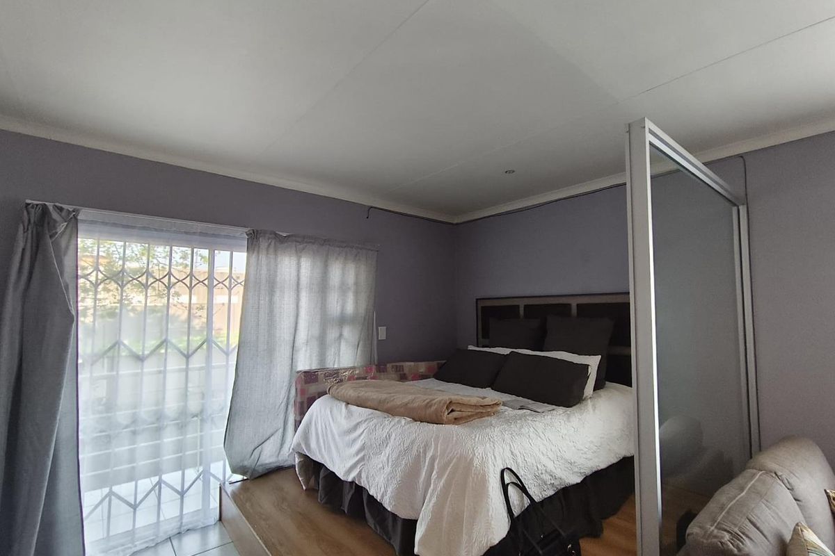 Bedroom featuring a raised wooden platform, sliding glass door with security gate, and a built-in room divider.