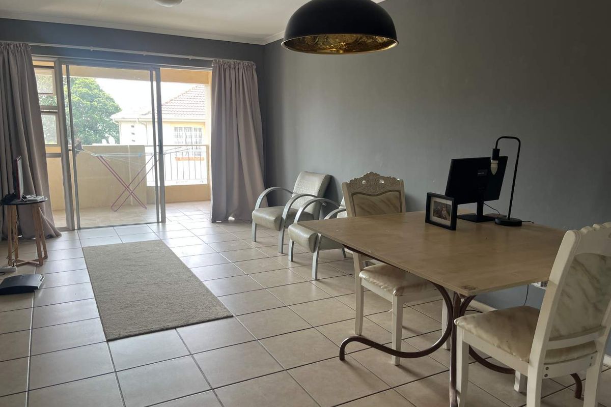 Spacious living area featuring neutral ceramic floor tiles, a large sliding glass door leading to a balcony, and modern grey wall finishes.