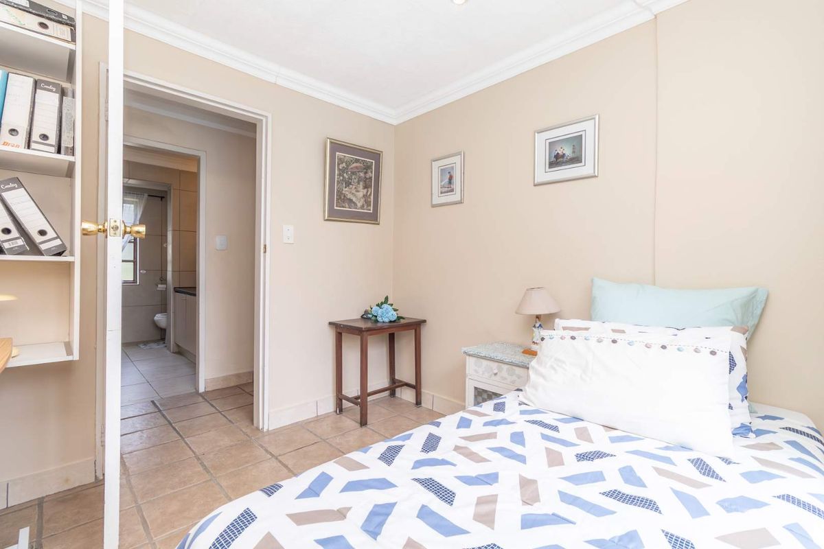 A bedroom featuring tiled flooring and built-in shelving, with an adjacent view into a tiled bathroom.