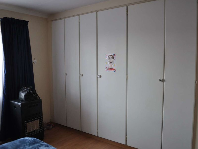 A bedroom featuring extensive floor-to-ceiling built-in cupboards and laminate flooring, providing ample storage space.