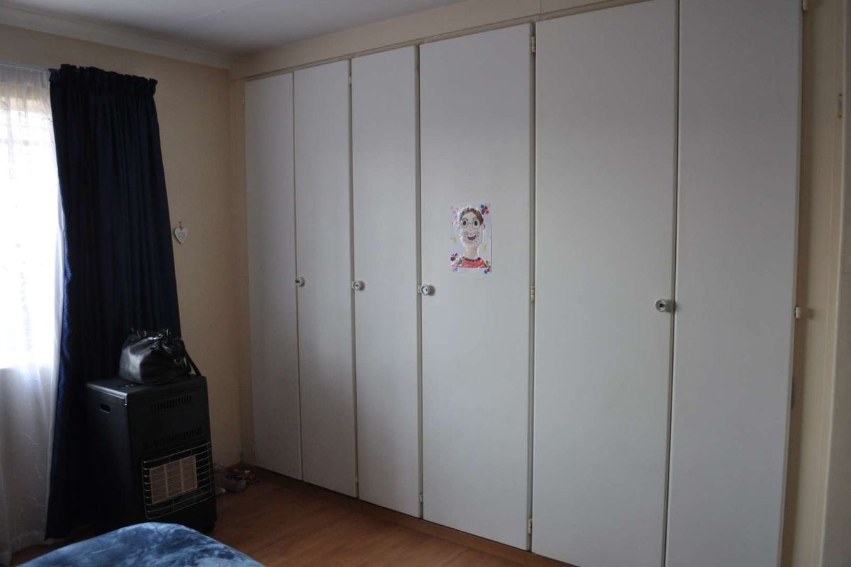 A bedroom featuring extensive floor-to-ceiling built-in cupboards and laminate flooring, providing ample storage space.
