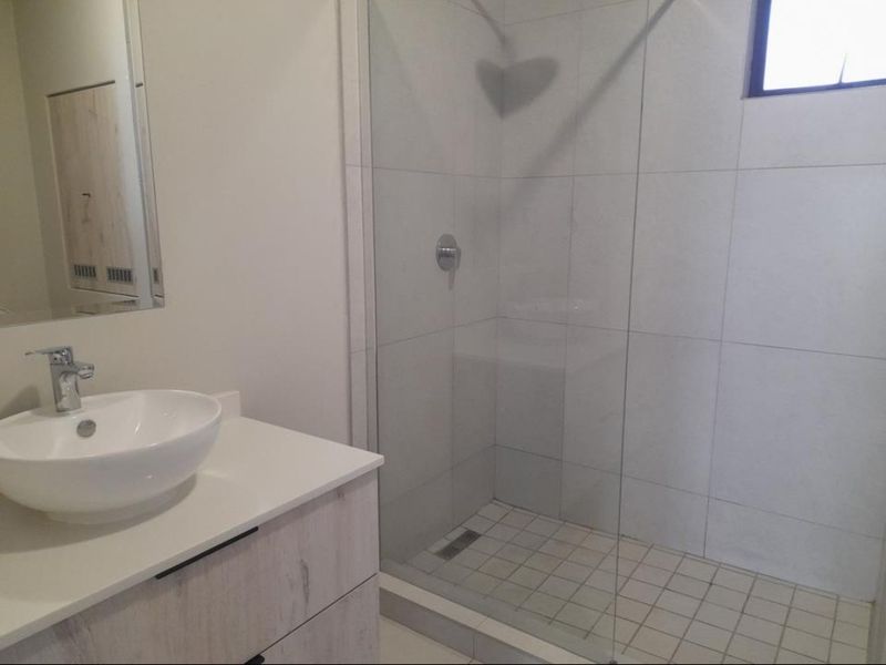 Modern bathroom featuring a walk-in shower with glass screen, a contemporary vessel sink vanity, and clean tiled finishes.