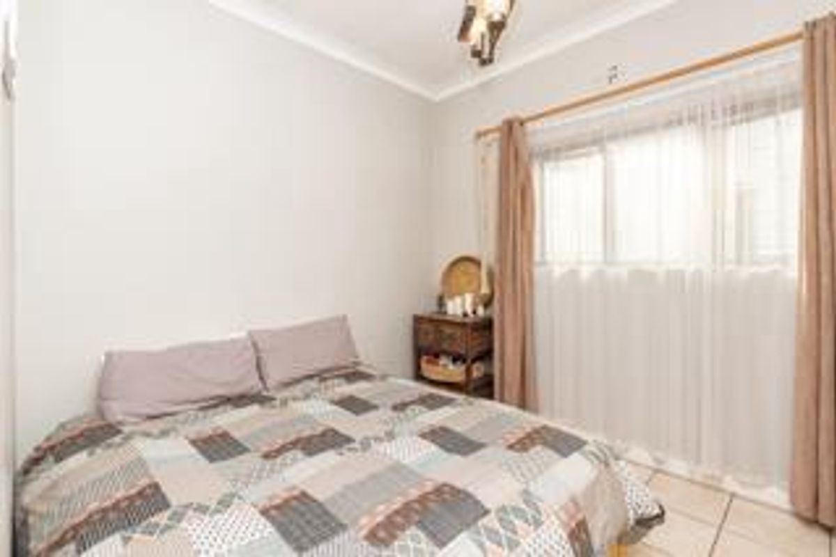A functional bedroom featuring tiled flooring and neutral wall finishes, providing a clean and simple space ready for personalization.