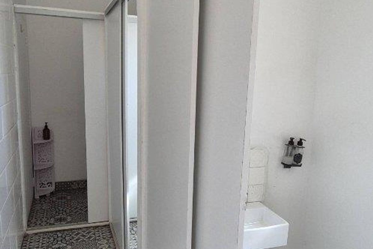 A functional bathroom featuring patterned floor tiles, a wall-mounted basin, and sliding door partitions for privacy.
