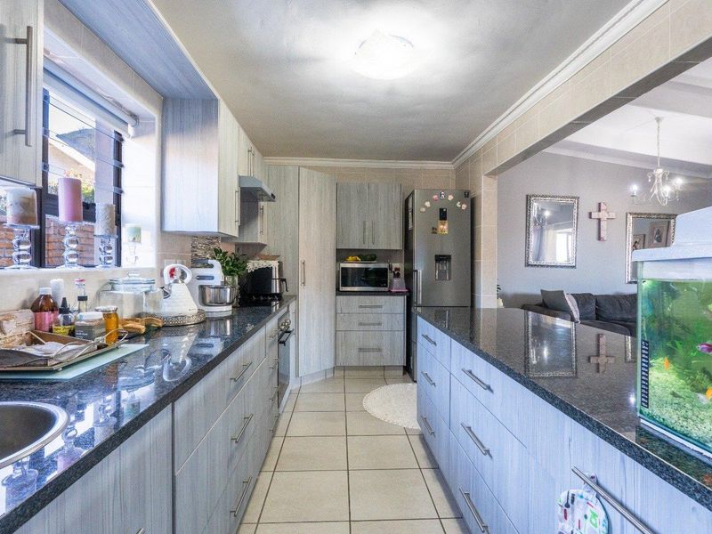A functional kitchen featuring granite countertops, ample built-in cabinetry, tiled flooring, and an open-plan layout connecting to the adjacent living area.