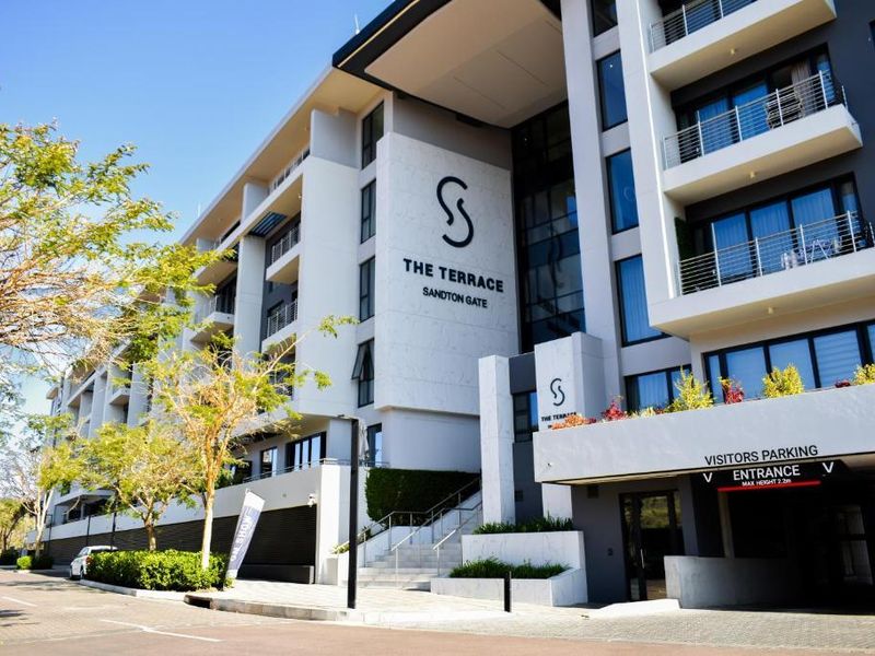 Modern apartment building facade featuring stone cladding, private balconies, and a dedicated visitors parking entrance at Sandton Gate.
