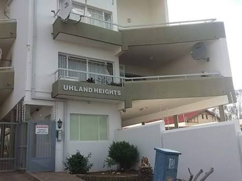 Front elevation of Uhland Heights apartment complex featuring multi-level balconies, secure gated access, and perimeter walling.