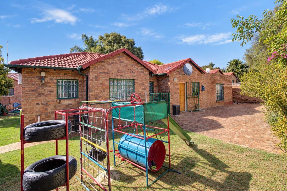 Rear view of a face brick townhouse featuring a paved patio area and a private garden space.