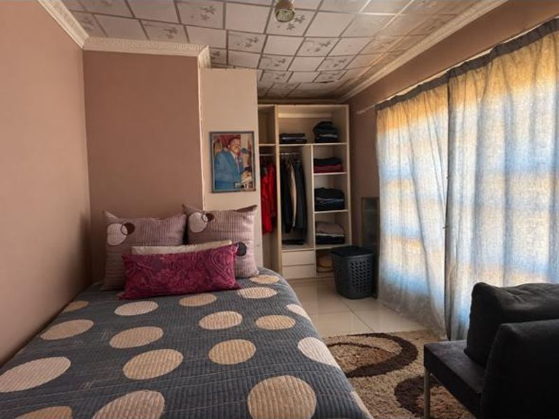 A bedroom featuring built-in wardrobe storage, crown molding, and tiled flooring. The room would benefit from cosmetic updates to the ceiling and finishes.
