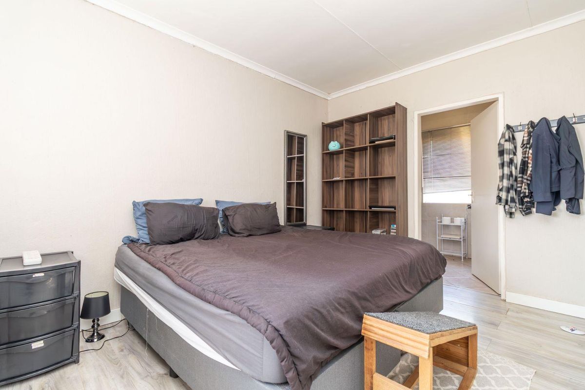 A bedroom featuring light-toned flooring and a doorway leading to an adjacent bathroom area.