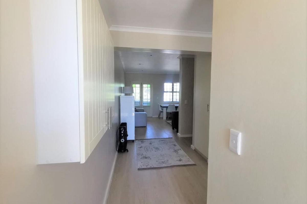 A bright hallway featuring light-toned laminate flooring and built-in cabinetry, providing a clean transition into the open-plan living and dining area.
