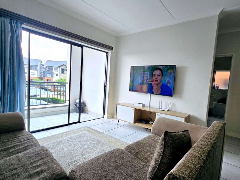 Bright living room featuring tiled flooring and large sliding glass doors providing direct access to a private balcony.