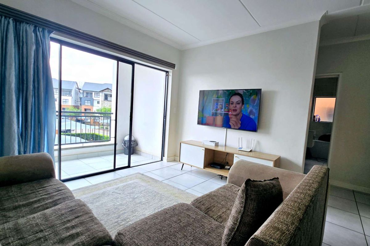 Bright living room featuring tiled flooring and large sliding glass doors providing direct access to a private balcony.