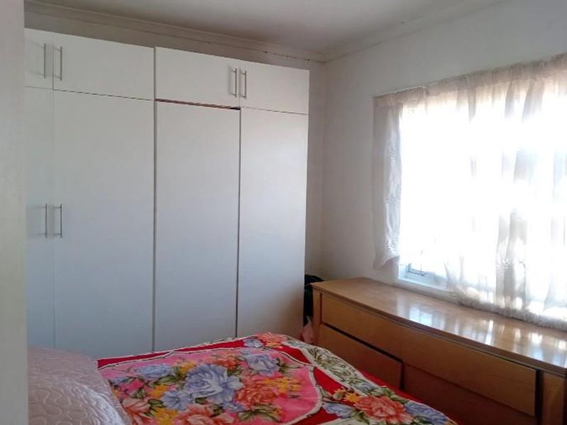 A bedroom featuring built-in cupboards and a window with natural light. The space requires minor maintenance to the ceiling cornice.