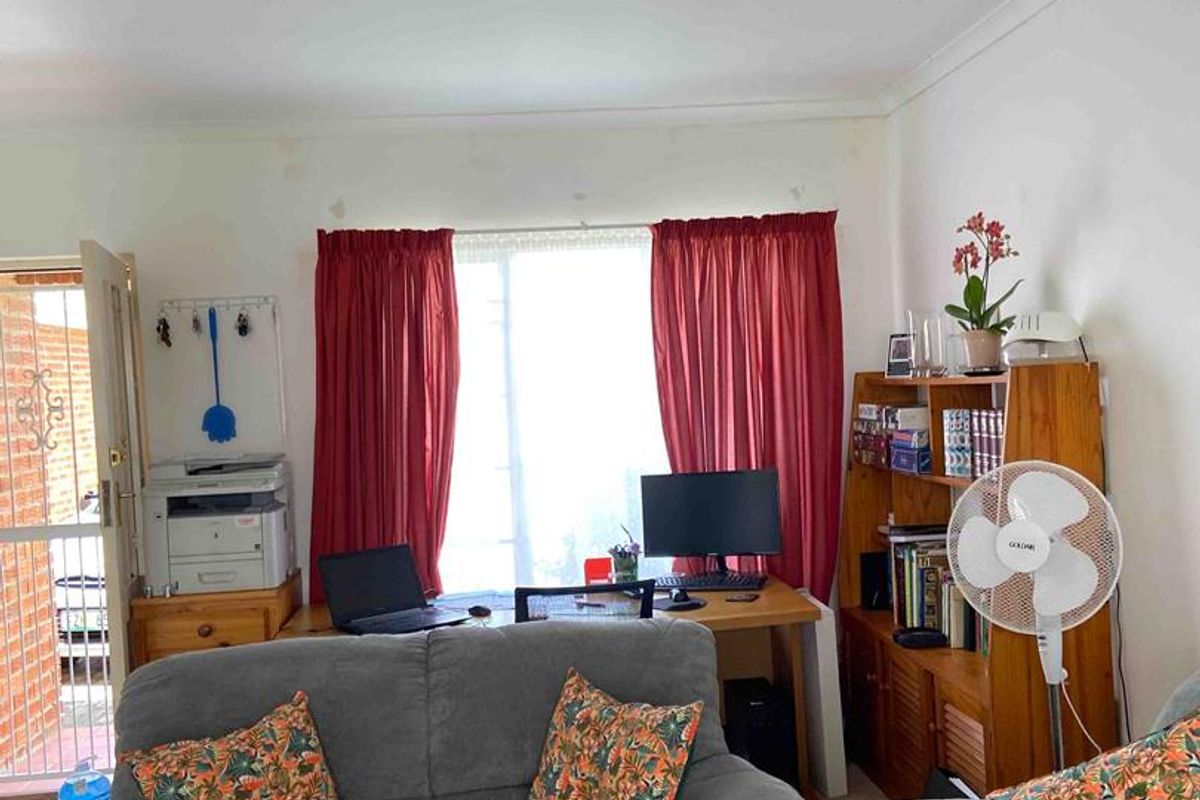 A living room area featuring a window with curtains and access to an exterior entrance.