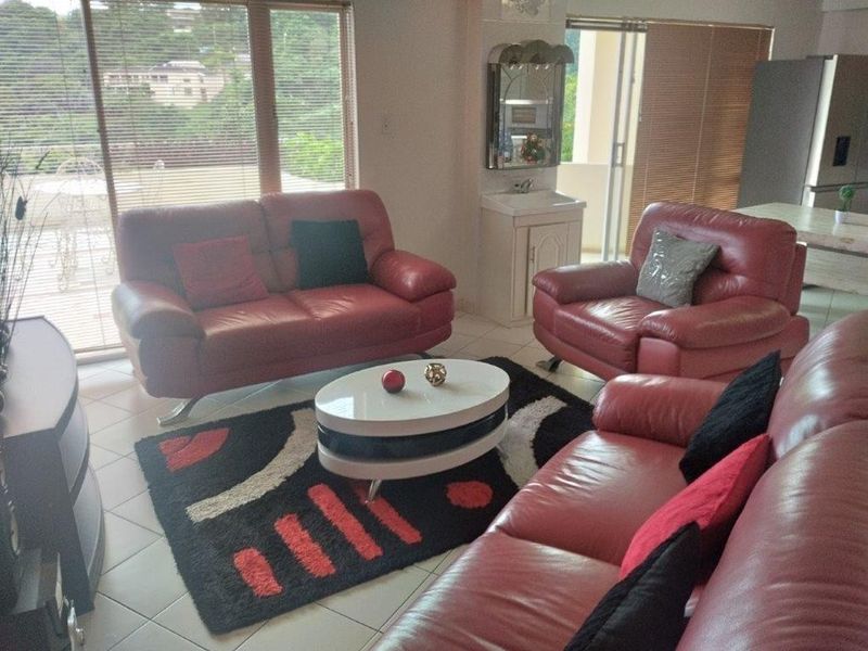 A living room featuring tiled flooring, large sliding glass doors with venetian blinds, and a built-in vanity basin area.