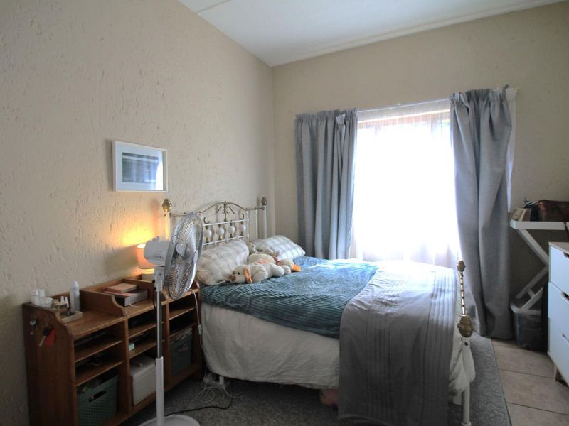 A functional bedroom featuring textured walls and tiled flooring, providing a comfortable and well-lit living space.