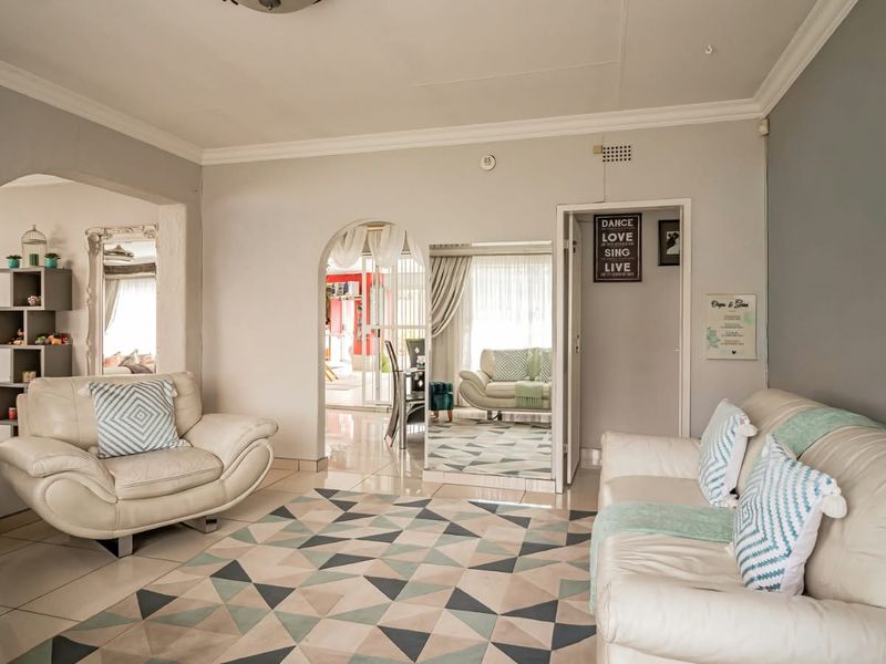 A bright and spacious living room featuring tiled flooring, decorative archways, and classic cove cornicing, creating a welcoming and well-connected living space.