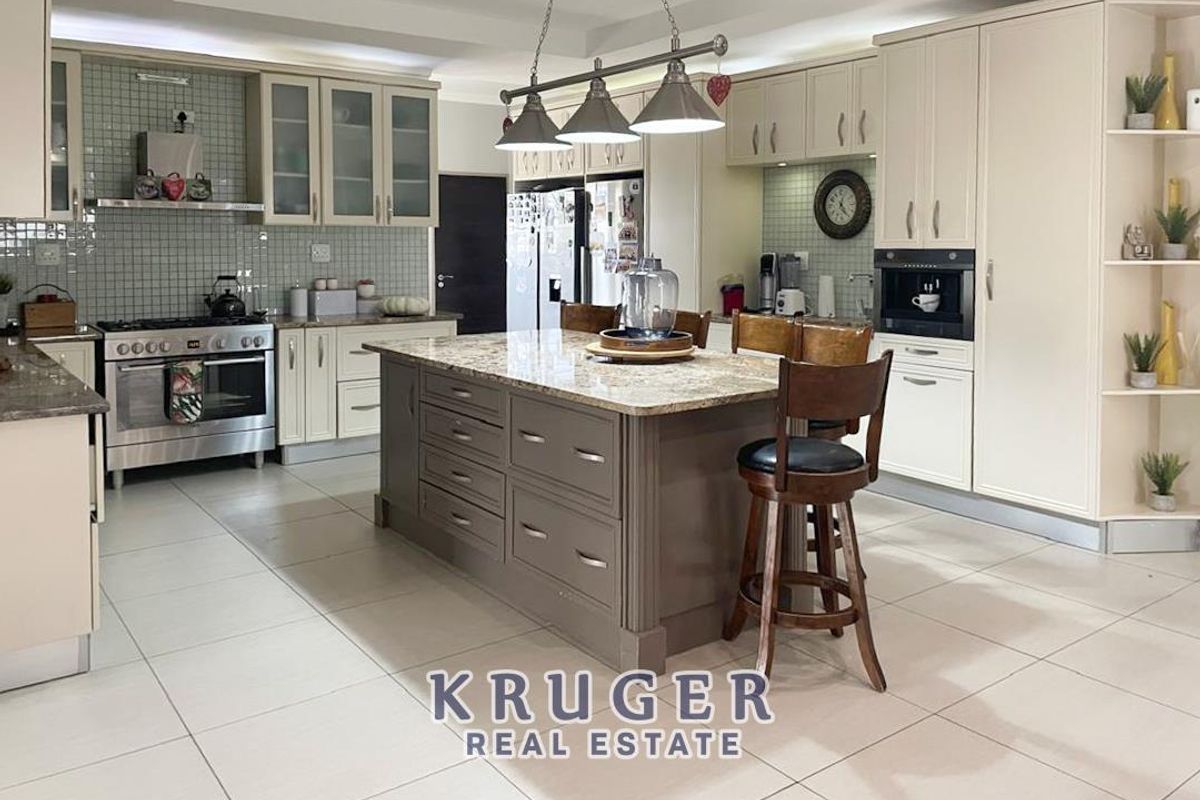 Spacious kitchen featuring a central island with stone countertops, built-in cabinetry, stainless steel oven, and a tiled backsplash.