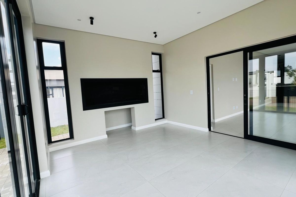 Modern living room featuring large format floor tiles, a built-in fireplace, and expansive black-framed sliding glass doors leading to the exterior.