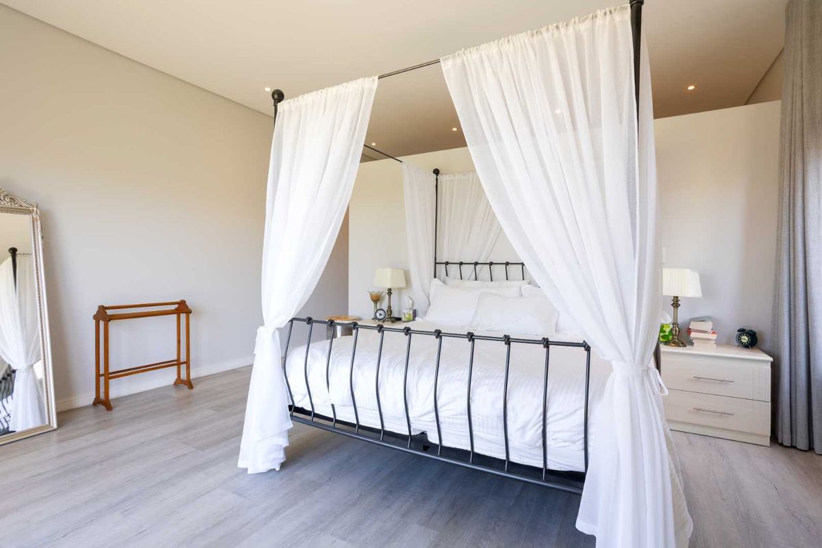 A spacious, well-maintained bedroom featuring modern laminate flooring and recessed downlighting, offering a clean and neutral aesthetic.