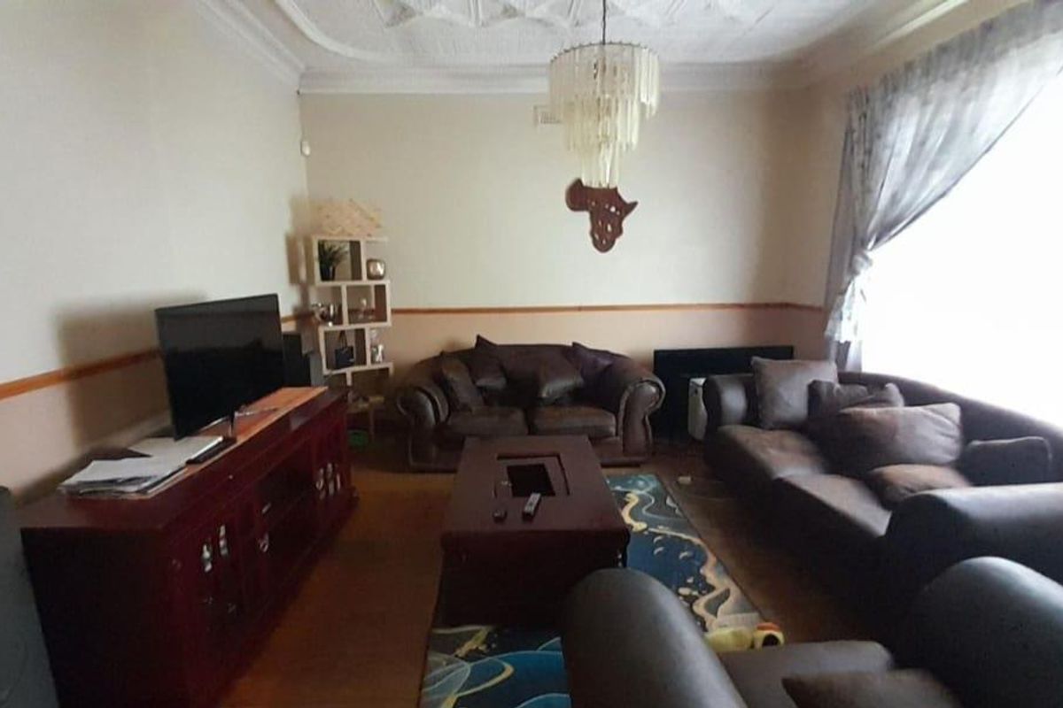 A traditional living room featuring decorative ceiling molding, a dado rail, and large windows allowing for natural light.