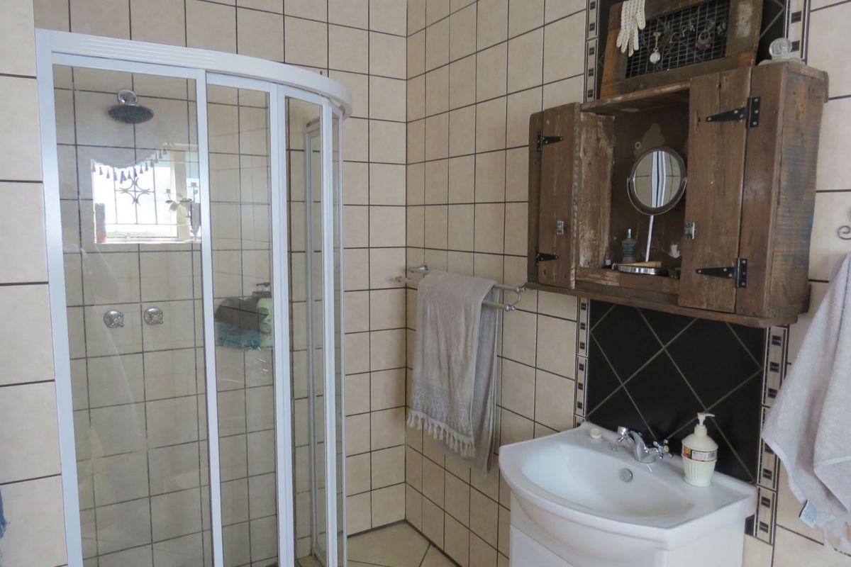 A functional bathroom featuring a corner shower enclosure, a wall-mounted vanity basin, and tiled wall finishes.